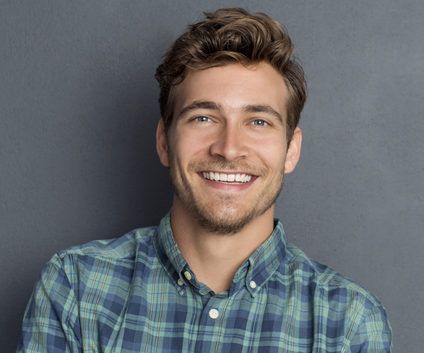 Young man with a confident smile after a professional smile makeover, showcasing bright white teeth and natural aesthetic