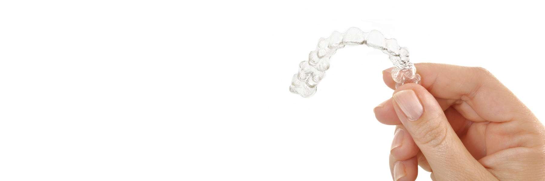 A hand displaying a clear aligner, a transparent dental tool designed for orthodontic treatment.