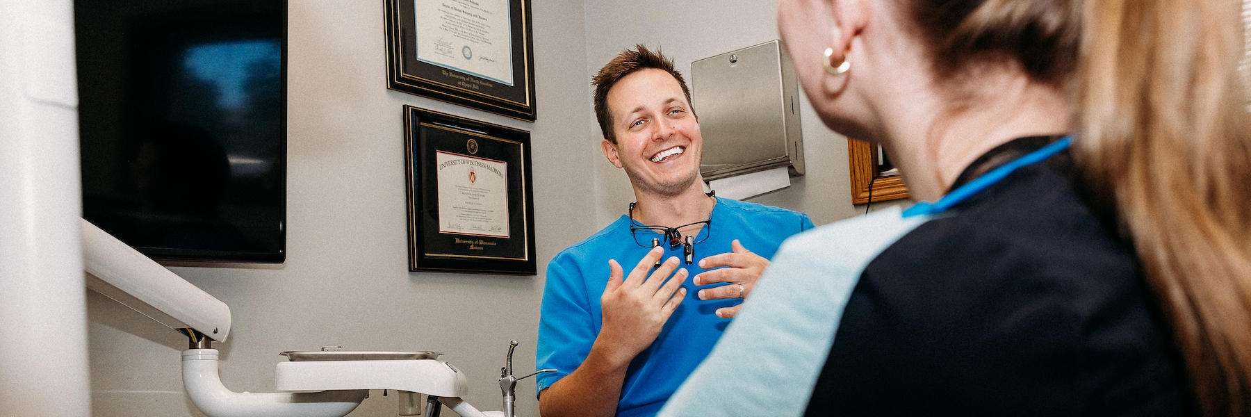 A man smiles while seated in a dental chair, reflecting satisfaction with his cosmetic dental treatment.