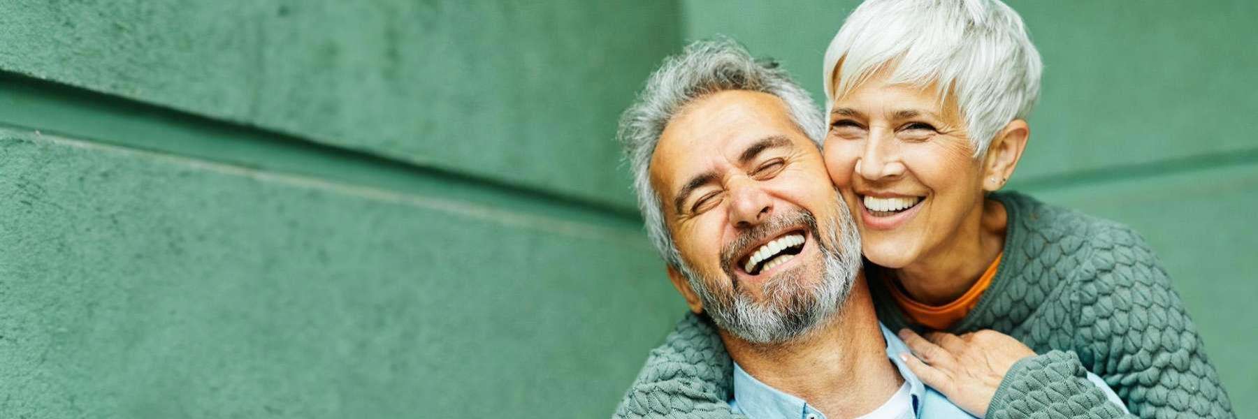 A joyful older couple shares a laugh, highlighting their beautiful smiles from dental implants at Scheske Family Dental.